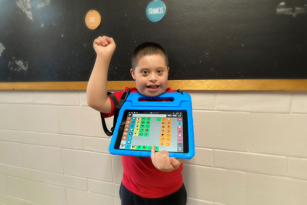 Child smiling, holding iPad