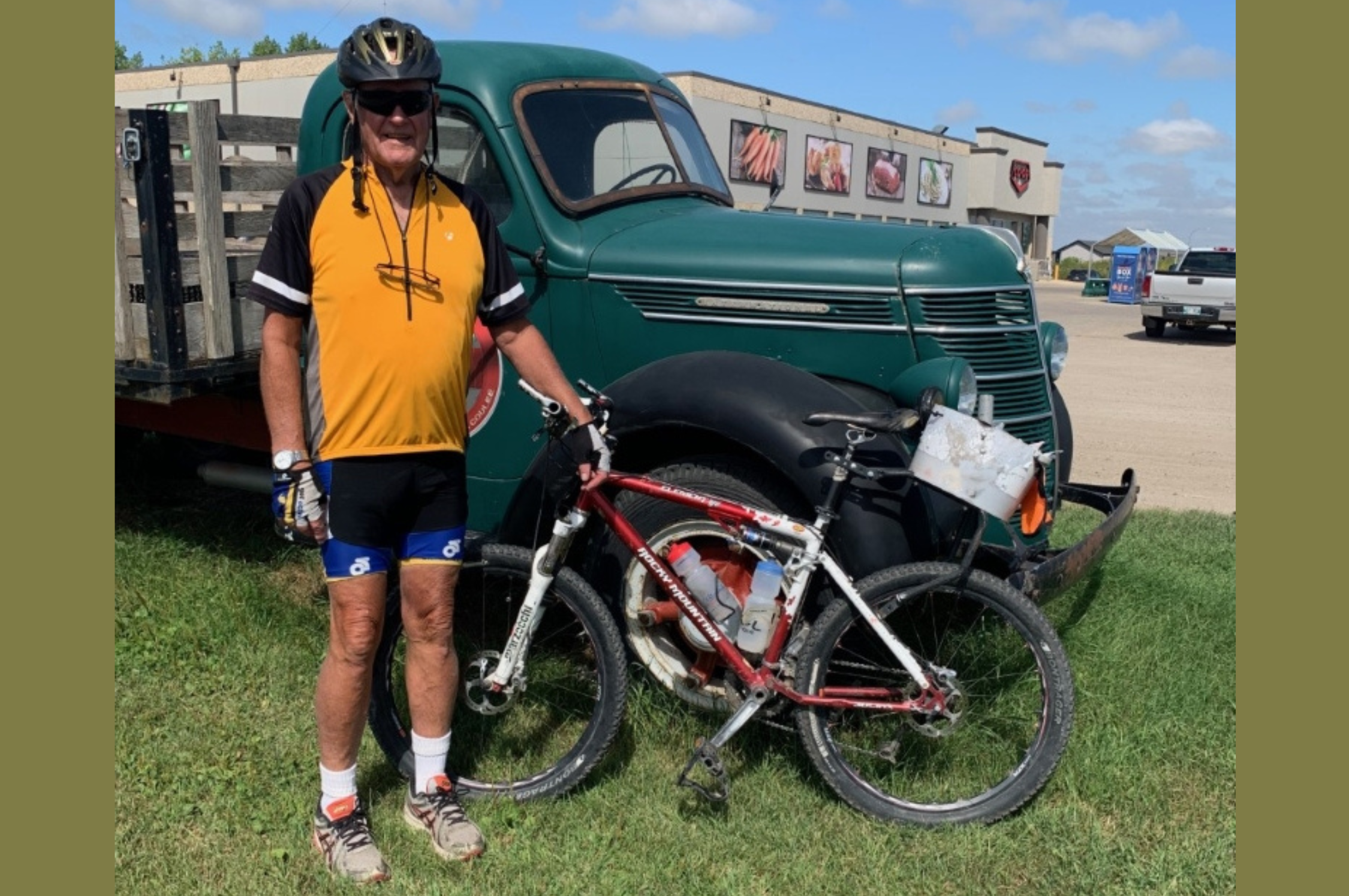 Bob Moore in full bicycle uniform poses next to his bike in front of a classic truck.