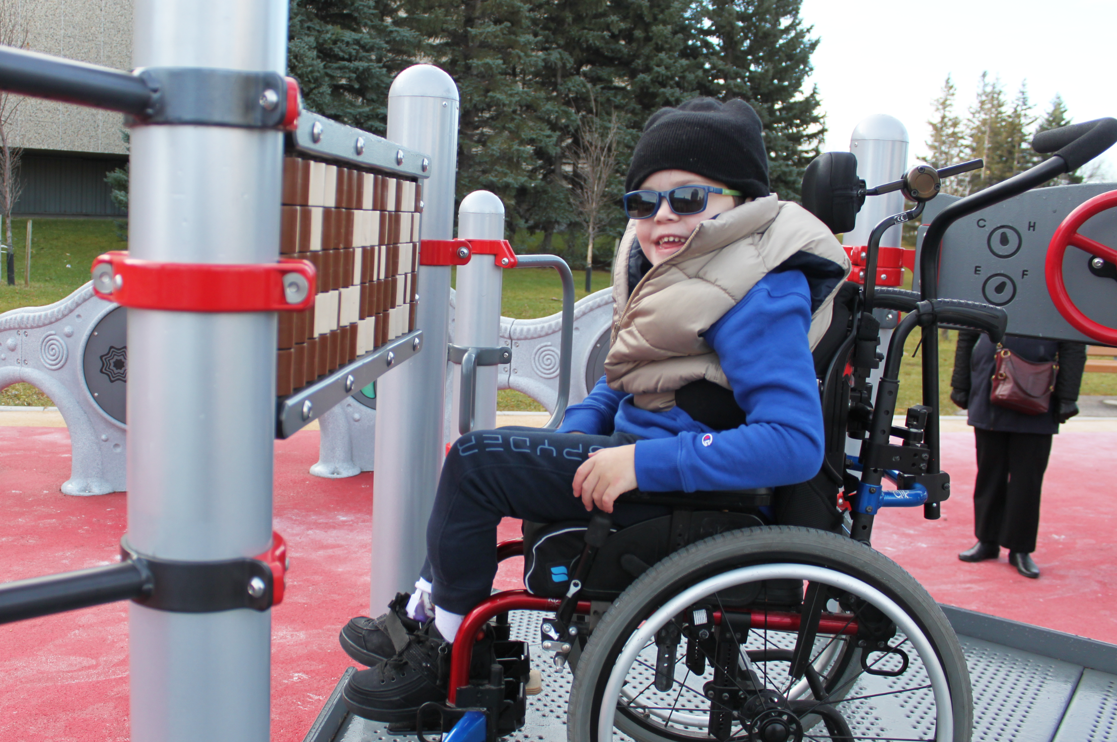 Young child in wheel chair plays with adapted playground feature.